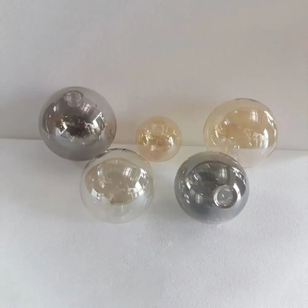 Set of five modern clear and smoked glass shade replacement globes with smooth reflective surfaces for living room lighting