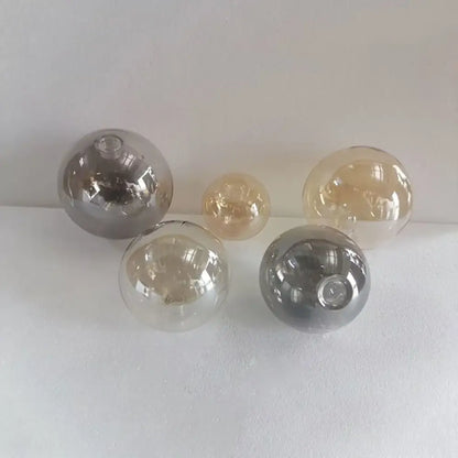 Set of five modern clear and smoked glass shade replacement globes with smooth reflective surfaces for living room lighting