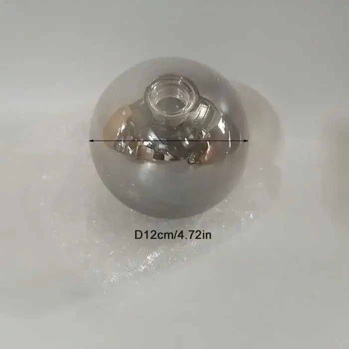 A clear spherical glass shade replacement with a threaded metal cap for modern living room globe lighting