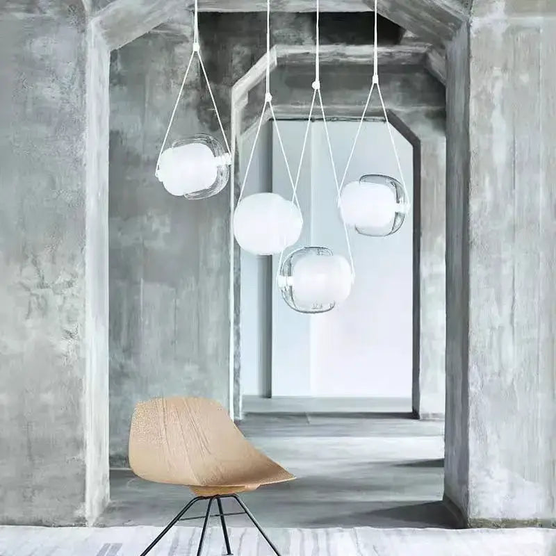 Modern colorful Czech glass capsule pendant light with clear glass spheres and white fabric cords in concrete archway