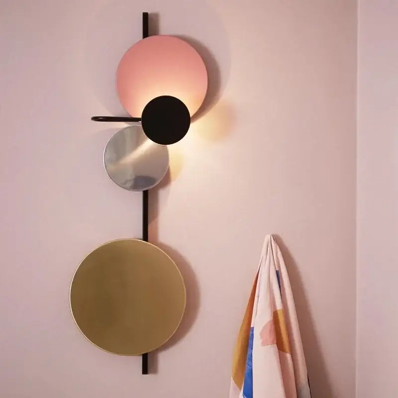 Modern colorful geometric led wall lamp with stacked circular shades in matte pink black mirrored silver and gold finishes
