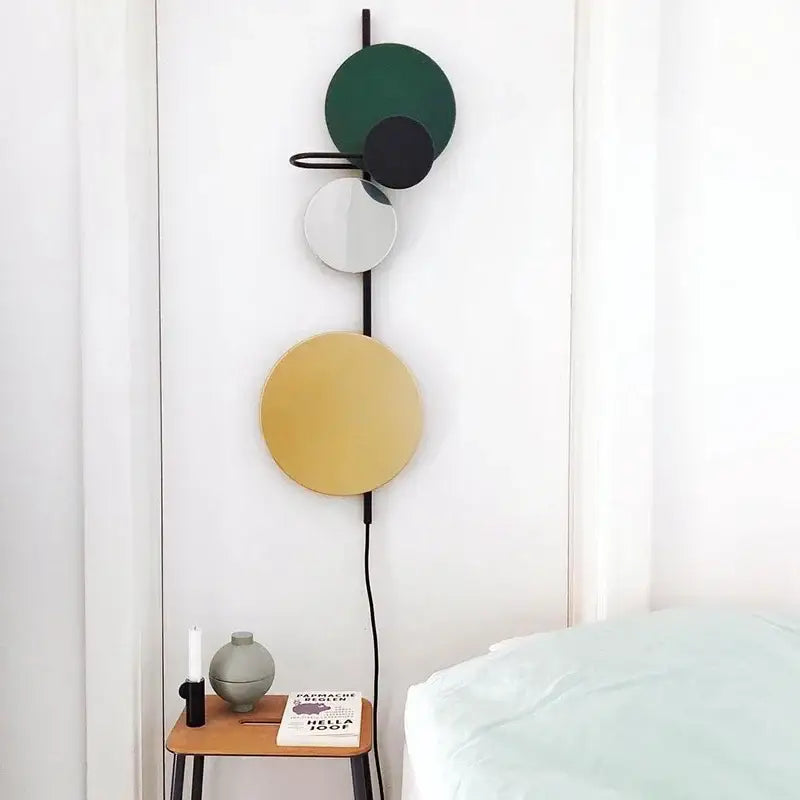 Modern colorful geometric led wall lamp with stacked green black and gold discs on a sleek black metal frame for bedroom decor