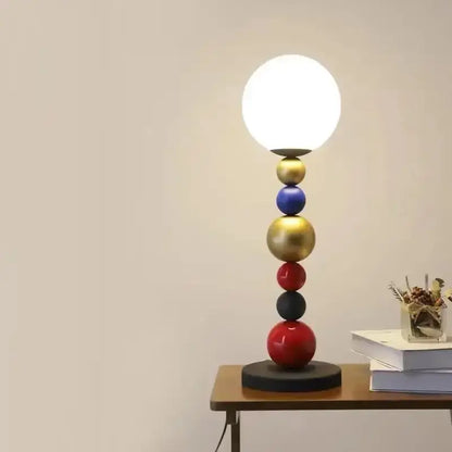 A modern floor lamp with colorful glass ball accents in gold blue red and black and a white globe shade for living room