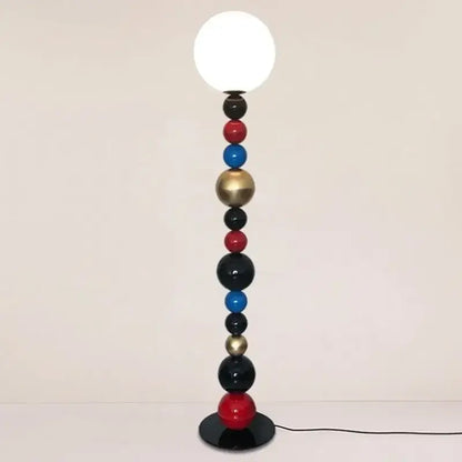 A modern floor lamp with colorful glass ball spheres in red blue black and gold supporting a white globe bulb for living room