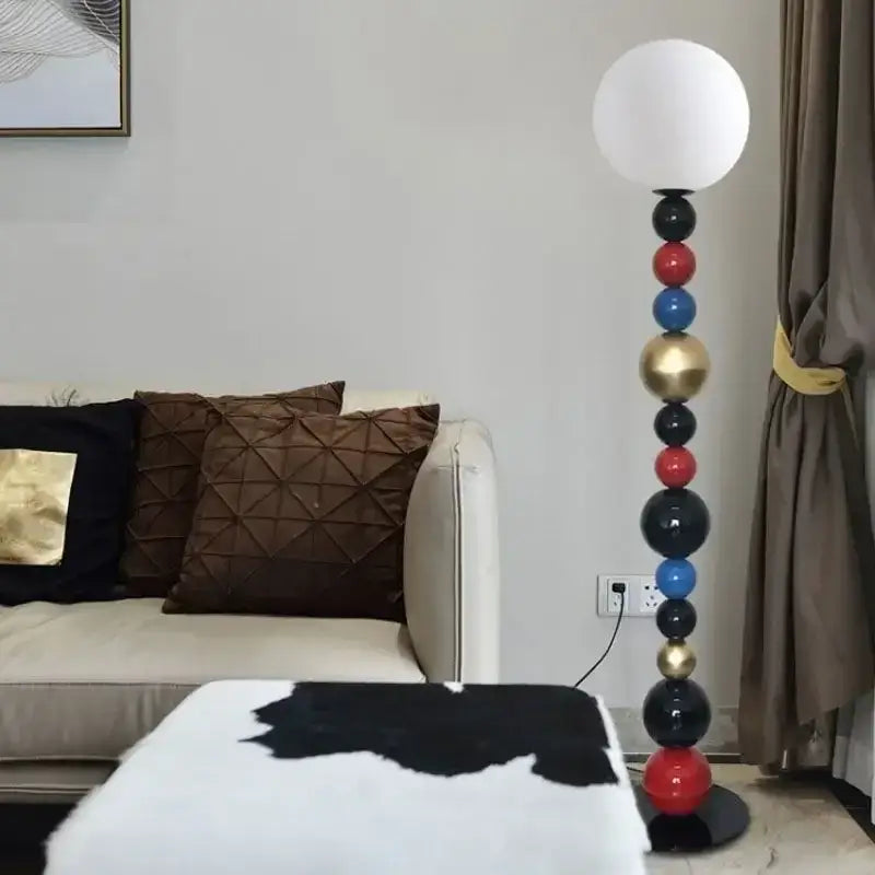 Modern floor lamp featuring a white spherical shade and a tall stacked column of colorful glass ball spheres