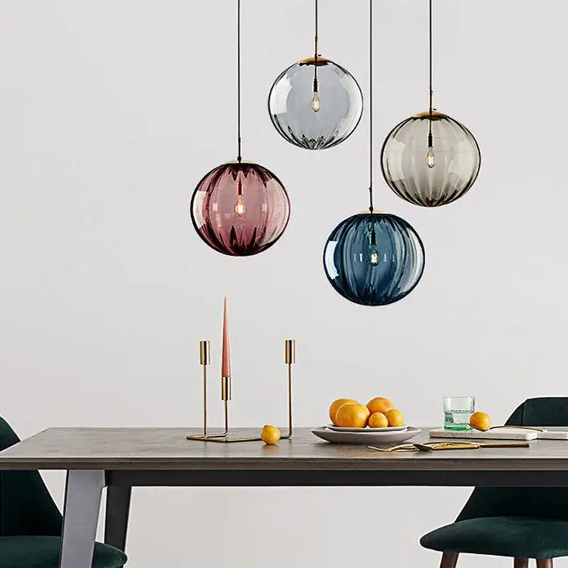 Four spherical frosted glass ball lustre pendant lights in gray rose and blue hang above a dining table