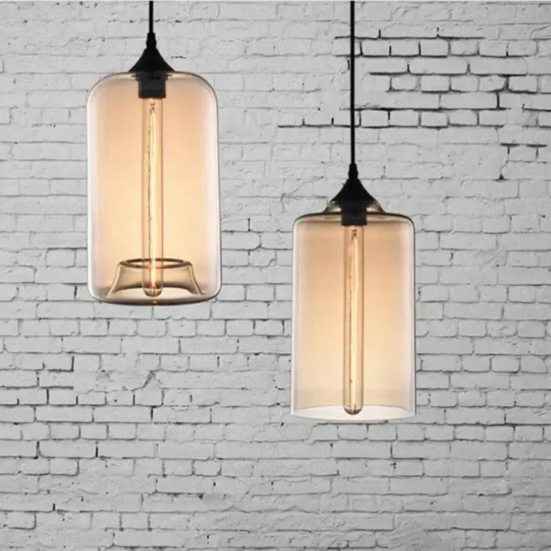 Two amber-tinted glass bowl pendant lights with exposed filament bulbs and black metal decorbites fixtures for kitchen use