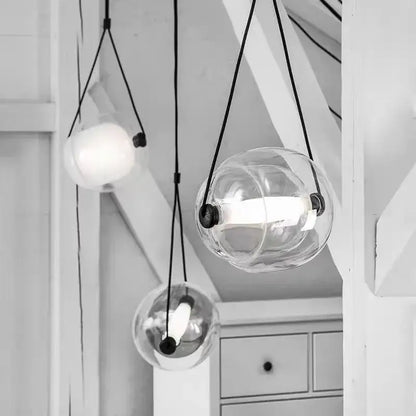 Modern colorful glass capsule led pendant light featuring clear glass globes with black cords and metal fixtures for kitchen bar