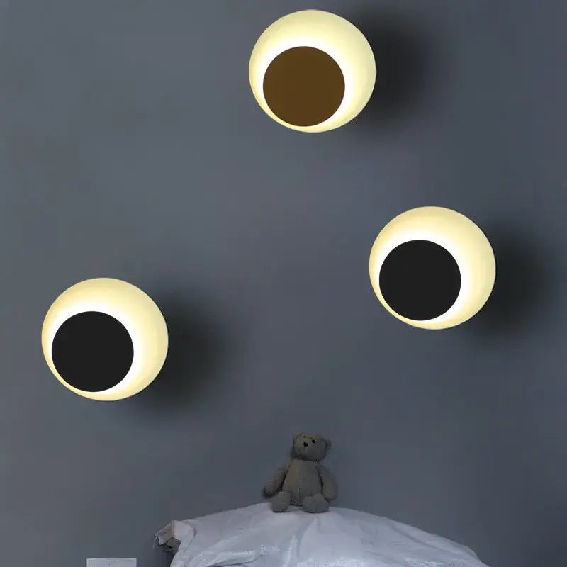 Three round glowing led wall lamps with cream outer rings and dark centers for bedroom and living room use