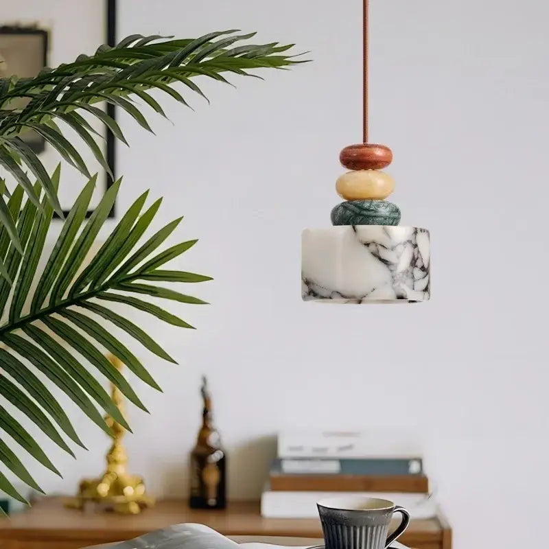A modern pendant lamp with a white marble base and decorbites colorful stone led orbs for dining room decor