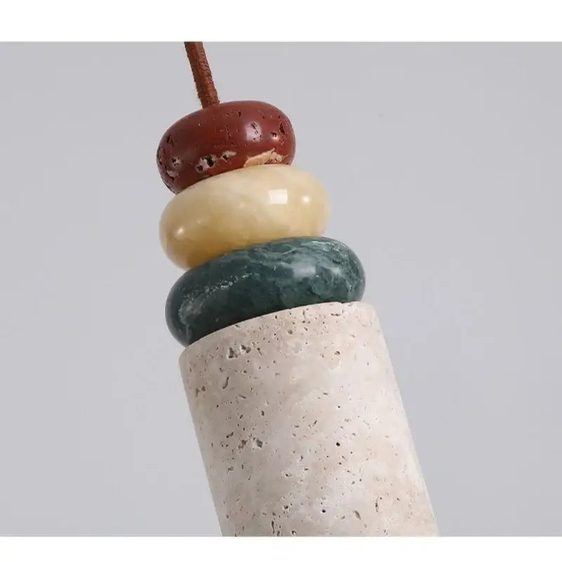 Modern colorful stone led pendant light with stacked reddish brown creamy yellow and deep green stones on concrete base