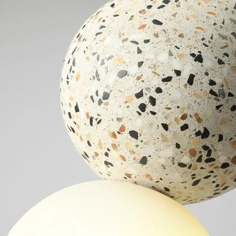 Modern pendant light with spherical terrazzo lampshade in iron finish featuring black beige and tan speckles