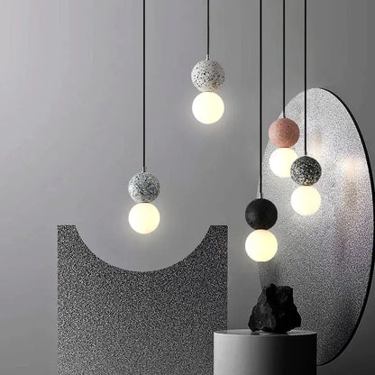 Modern pendant light with speckled concrete spheres and glowing glass orbs in iron finish for dining room use