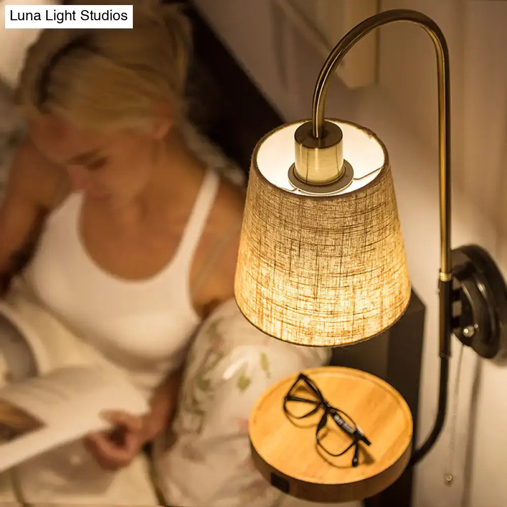 Modern conical fabric wall mount lamp with warm-toned linen shade brass arm pull chain and wood shelf for bedroom lighting