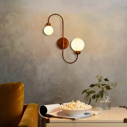 Modern copper living room spherical wall sconce with two curved arms and frosted white glass globe shades