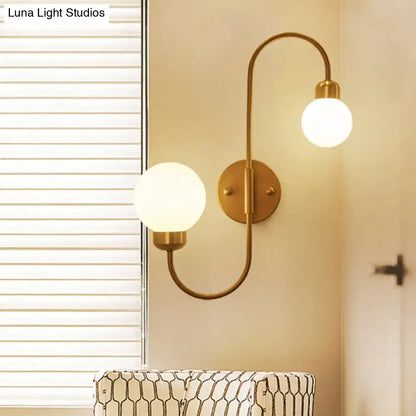 Brass-finished modern white glass spherical wall sconce with two curved arms for living room lighting