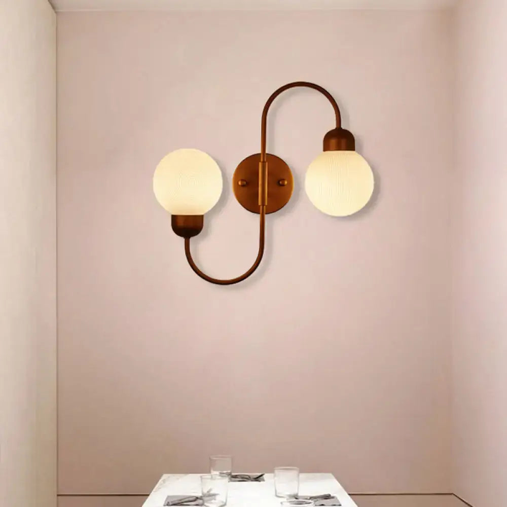 Modern living room spherical wall sconce with brass finish and two frosted white glass globe shades