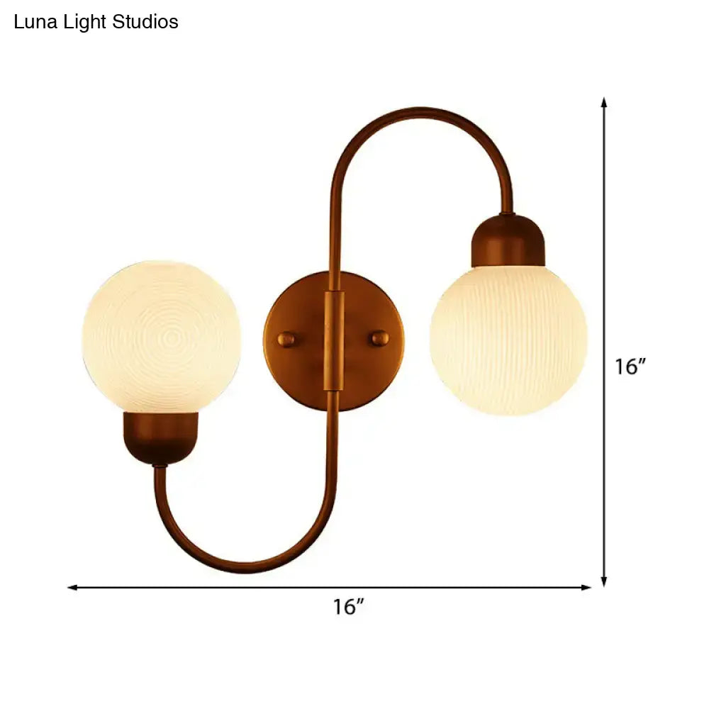 Antique brass-finished spherical wall sconce with modern white frosted glass shades for living room lighting