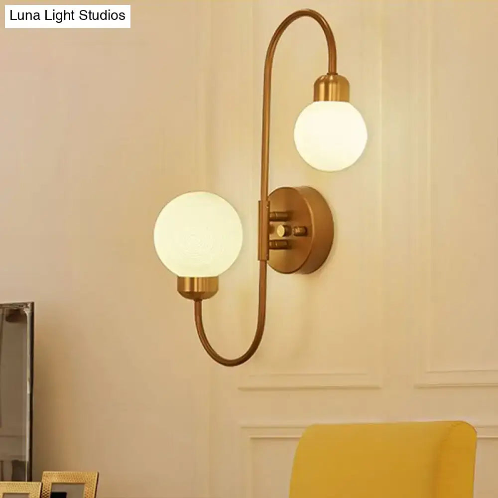 Modern brass-finished spherical wall sconce with two white frosted glass globes for living room lighting