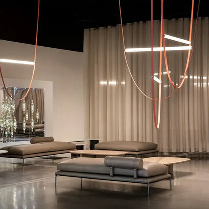 Modern taupe leather daybed with minimalist metal frame and cylindrical bolster pillows paired with decorbites bell pendant light