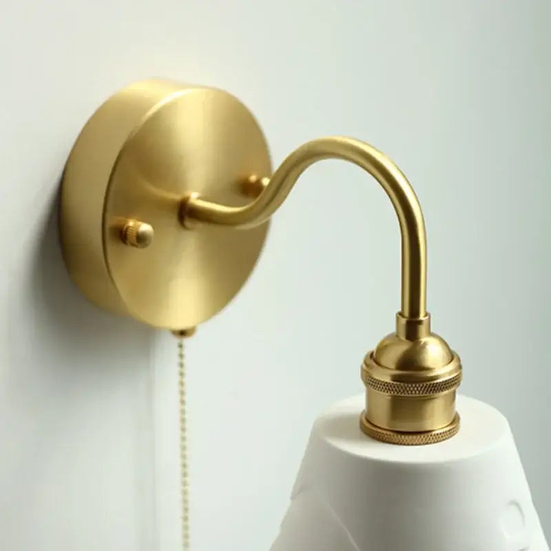 Modern copper wall sconce with gold-toned brass curved arm textured base and clear glass decorbites clear glass pull chain light
