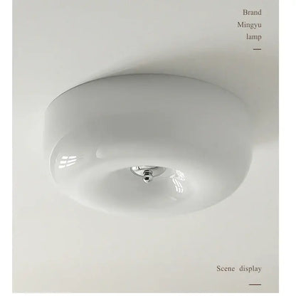A sleek minimalist cream bauhaus style ceramic ceiling lamp with a rounded glass dome and polished chrome fixture