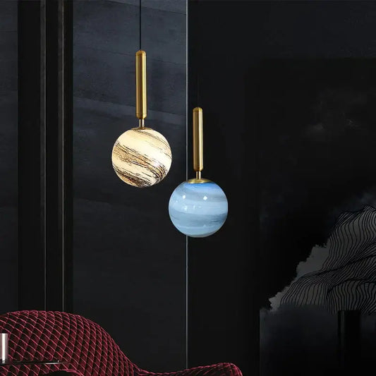 Two elegant glass planet pendant lights with cream marble and translucent blue shades for modern bedroom lighting