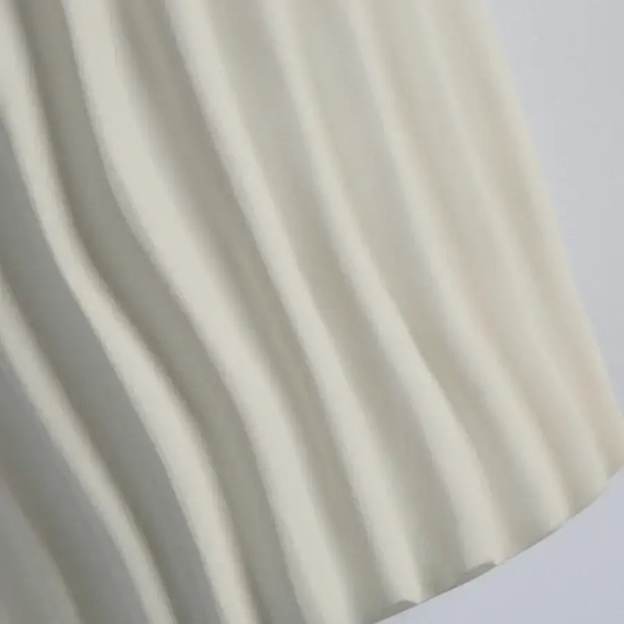 Modern cream ceramic ridged led wall lamp featuring soft pleated fabric with flowing vertical folds for bedroom sconce