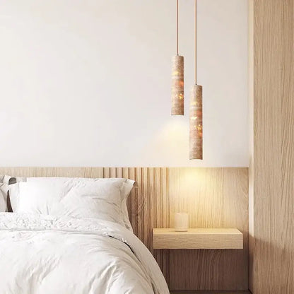 Two modern cream concrete cylindrical pendant lights with warm textured finish provide lighting area above the bed