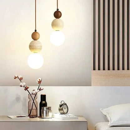 Two modern pendant lights with wood accent and cream stone tones suspending glowing bulbs for dining room use