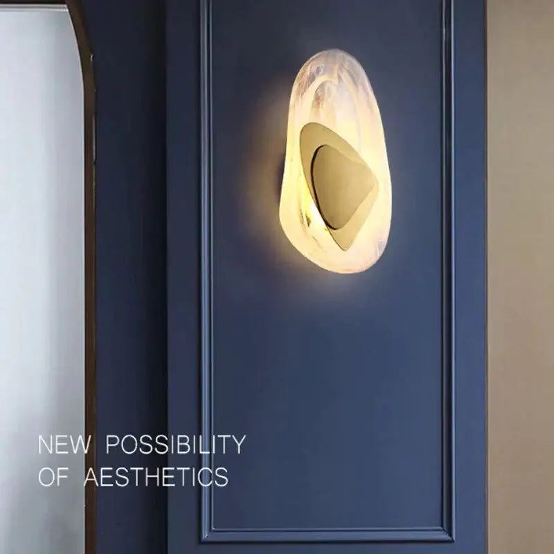 A modern creative minimalist glass wall lamp with amber glass and gold-toned accent for bedroom bedside lighting
