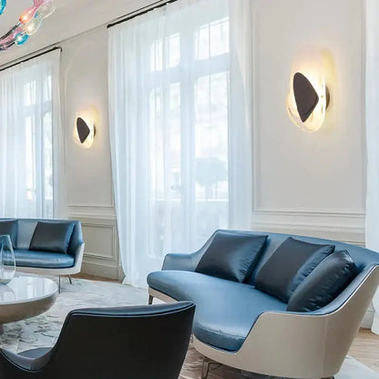 Modern creative minimalist glass wall lamp beside a blue leather sofa with white frame and black cushions for bedroom lighting