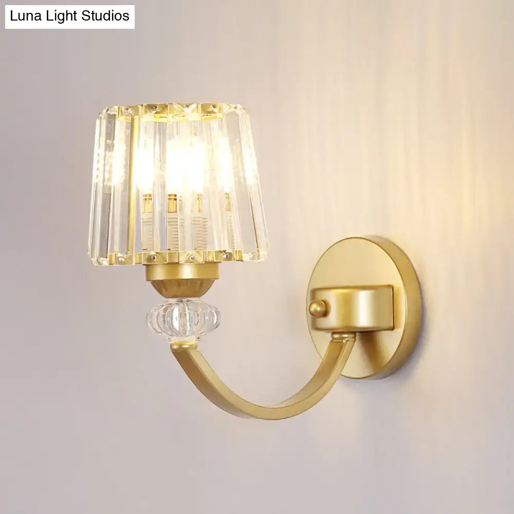 Gold-finished wall lamp with black gold curved arm featuring a faceted crystal shade and clear glass globe accent