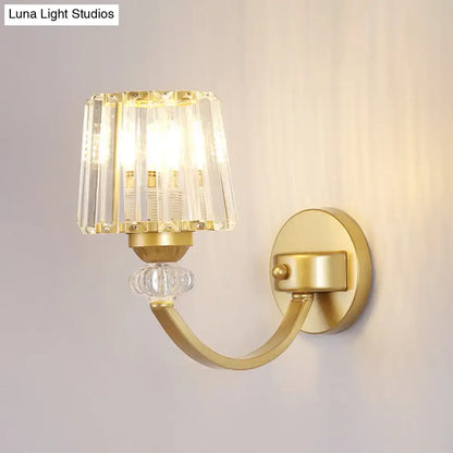 Gold-finished wall lamp with black gold curved arm featuring a faceted crystal shade and clear glass globe accent