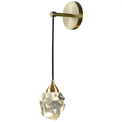 A modern crystal golden wall sconce with a brass base and faceted glass pendant for warm bedroom lighting decorbites crystal golden