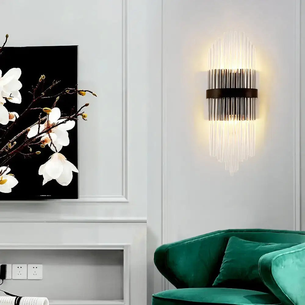 Modern crystal prism wall sconce with sleek black metal frame and metal square backplate emitting warm light