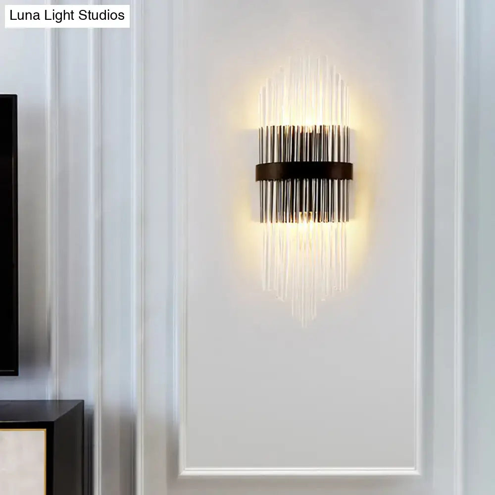 Modern crystal prism wall sconce with metal square backplate black frame and vertical glass rods emitting warm light