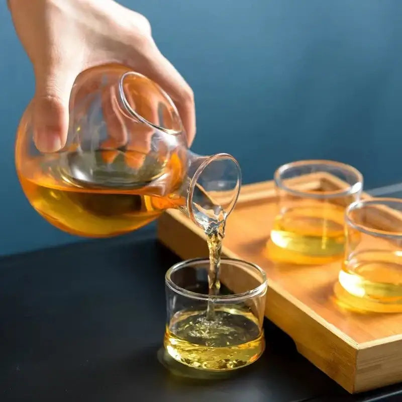Modern crystal sake ice jug clear glass teapot with curved spout pouring amber tea into matching glasses decorbites crystal sake