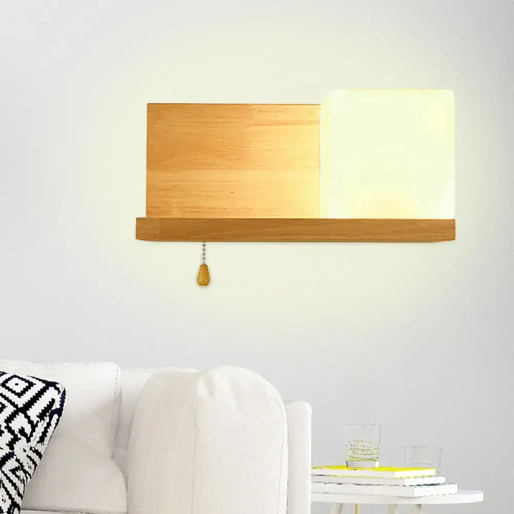 Modern cubic wall sconce light with warm-toned beige wood panel and frosted glass diffuser for bedroom use