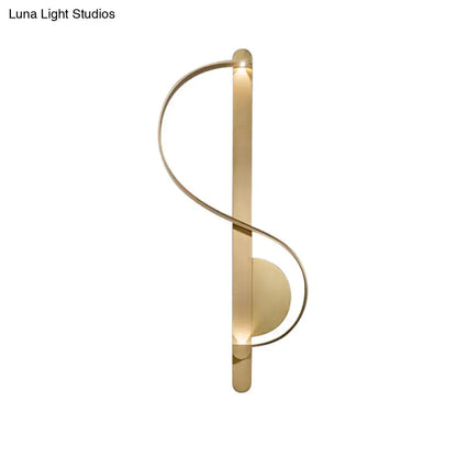 Gold-toned minimalist wall sconce with sleek curved design featuring warm white integrated lighting for bedroom use