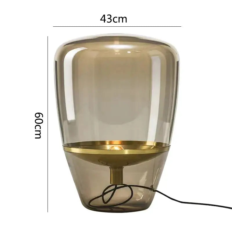 A sleek 60cm tall decorbites glass table lamp with translucent amber glass body and polished brass ring for bedroom lighting