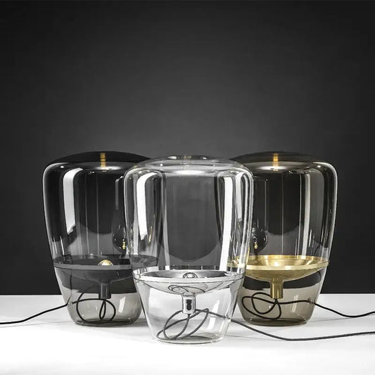 Three modern decorbites glass table lamps with cylindrical glass shades and metallic bases in black clear and gold finishes
