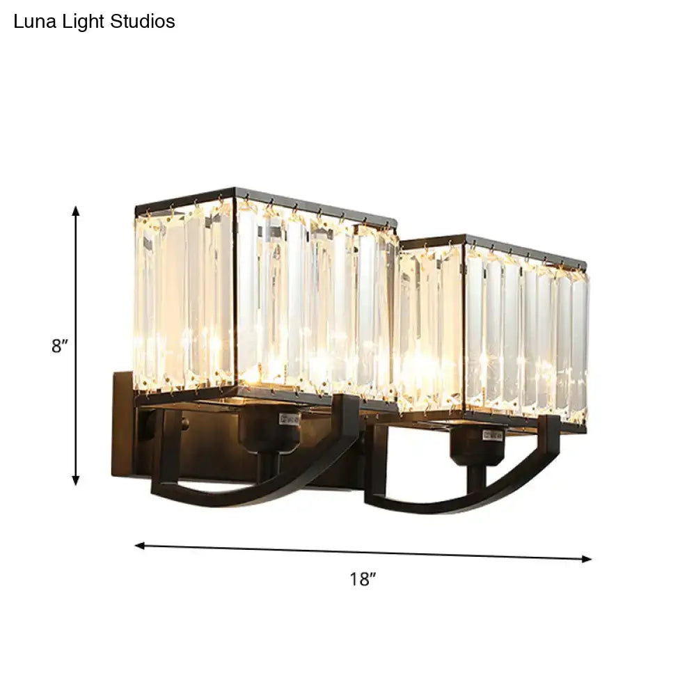 Modern dark bronze and crystal wall mount light with brass finish and two rectangular crystal panels emitting warm light