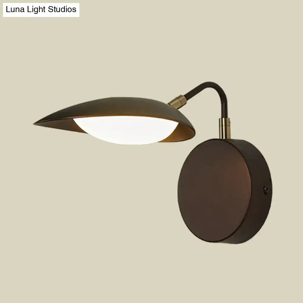Modern dark bronze oval wall mount sconce with a sleek curved arm and leaf-shaped shade for bedroom lighting