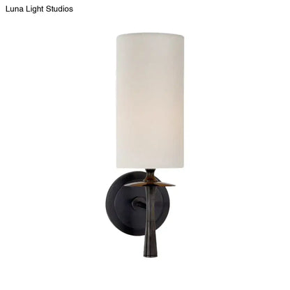 Modern dark bronze sconce light with white glass shade featuring a cylindrical fabric shade and leaf-like metal accent