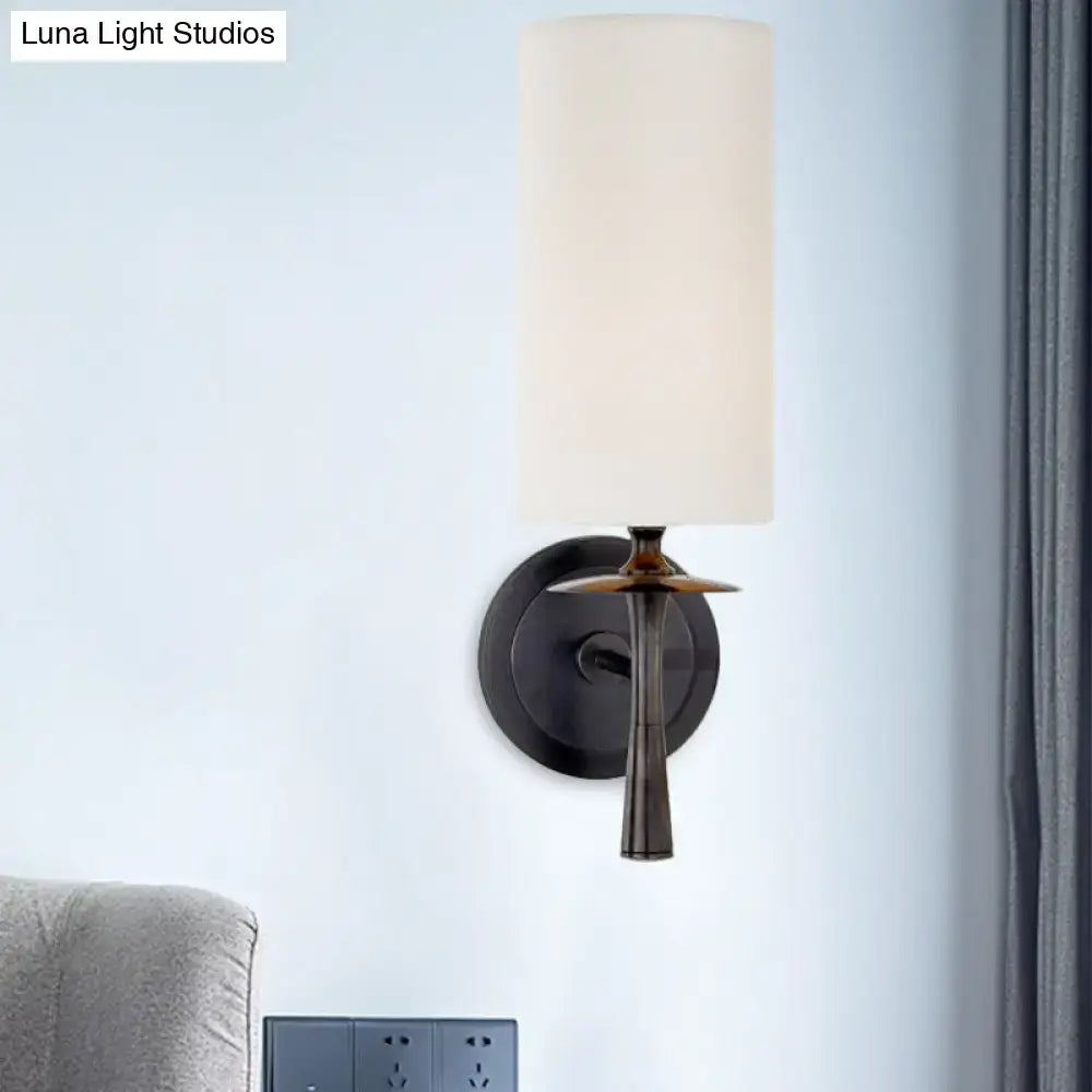 Modern dark bronze sconce light with a sleek matte black stem and tall white glass shade for bedroom use
