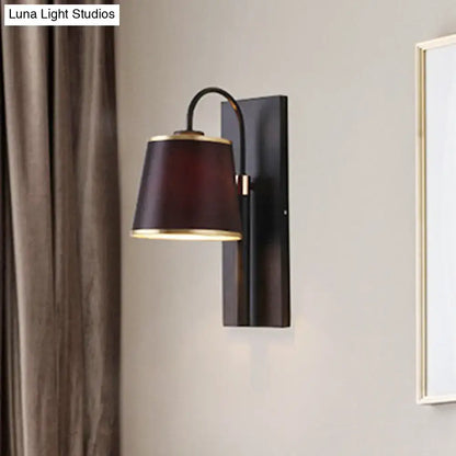 Modern dark brown fabric conical shade wall lamp with brass trim mounted on black metal fixture for living room use