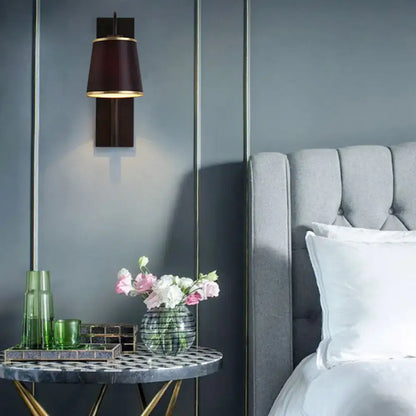 Modern dark brown wall lamp with gold trim and conical shade designed as a living room sconce