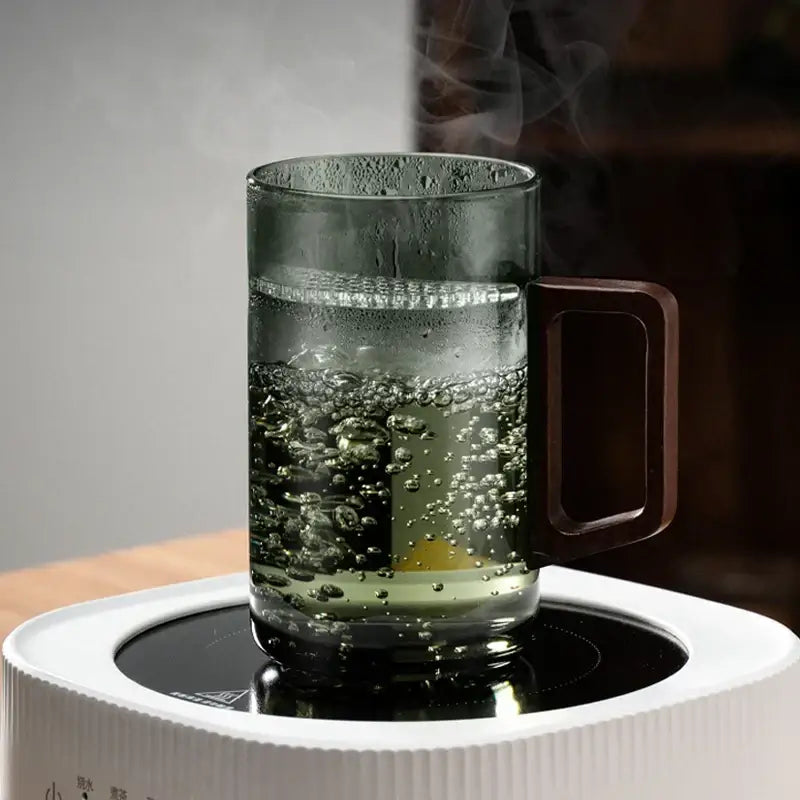 Modern dark green glass tea cup set with wooden handle filled with steaming water and bubbles for dining room use