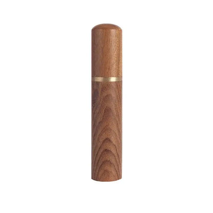 A sleek cylindrical wooden espresso coffee stirrer with warm amber finish and a thin gold needle distributor band